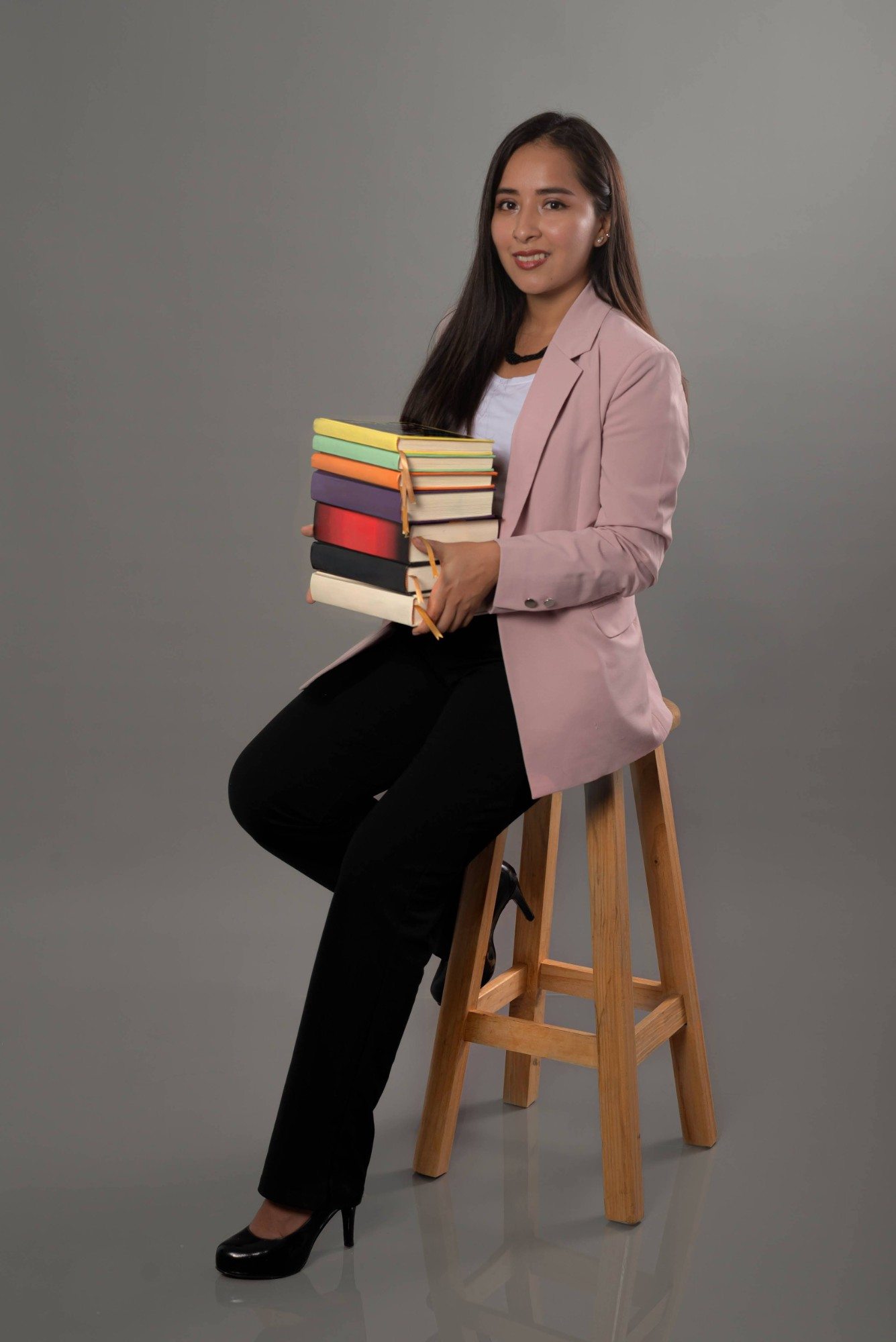 Lucia Bojorquez, editora de Lunagrama, sostiene una pila de libros de colores