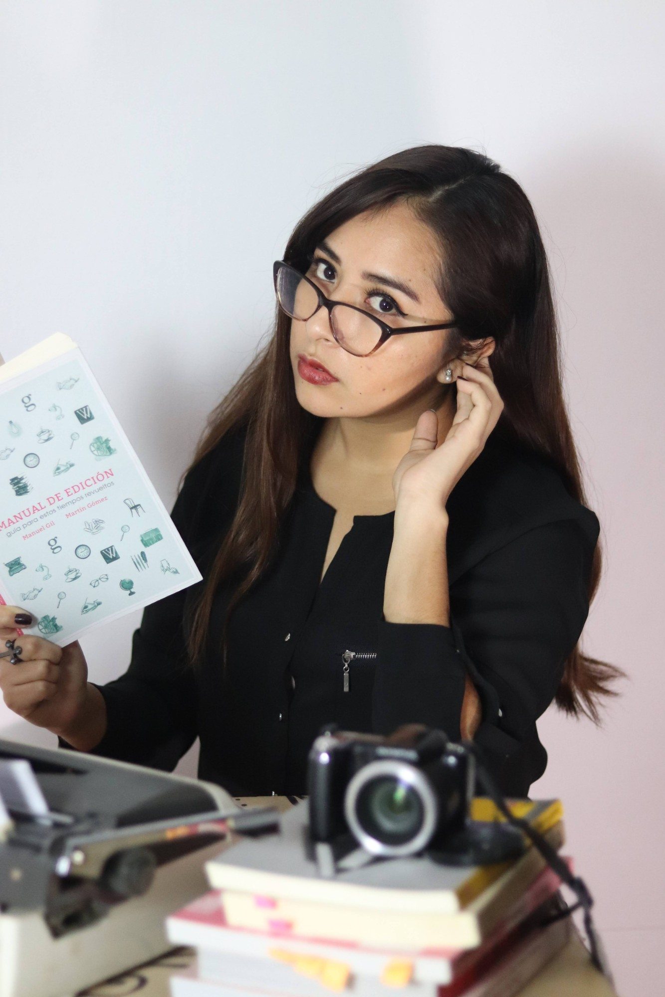 Lucia Bojorquez sostiene un ejemplar del Manual de edición junto a una máquina de escribir y una pila de libros